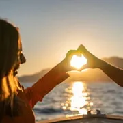 The golden sun setting behind Positano's church dome and pastel village, viewed from a private boat on a sunset boat charter along the Amalfi Coast from Positano