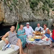 A private charter boat anchored off the Li Galli islands with the dramatic Amalfi Coast cliffs in the background — full-day private boat tour from Sorrento with Limoncello